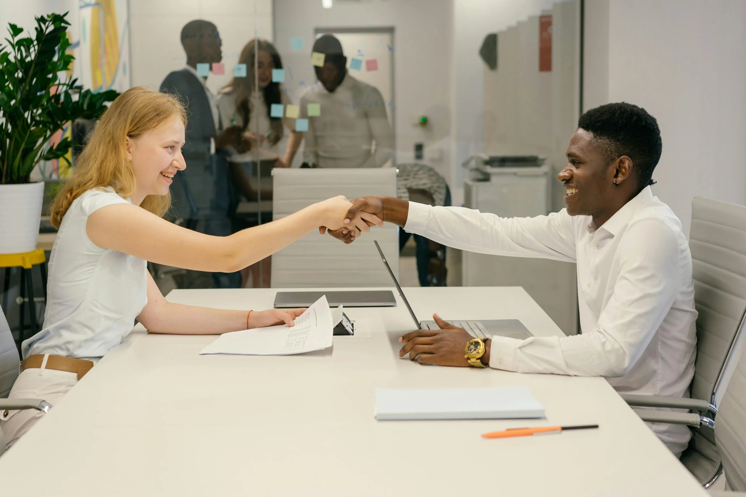 Free Business professionals completing a successful deal with a handshake in a modern office setting. Stock Photo